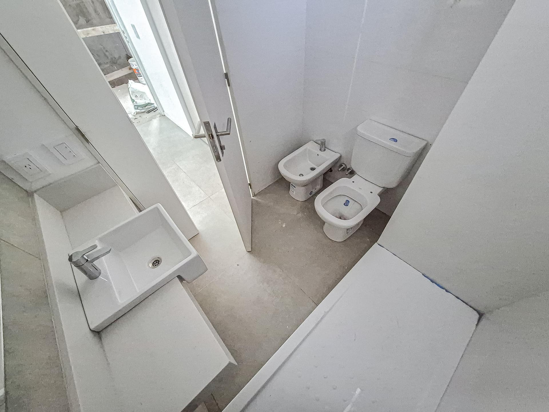 Baño con inodoro, bidet, lavatorio y bañera, con azulejos blancos.