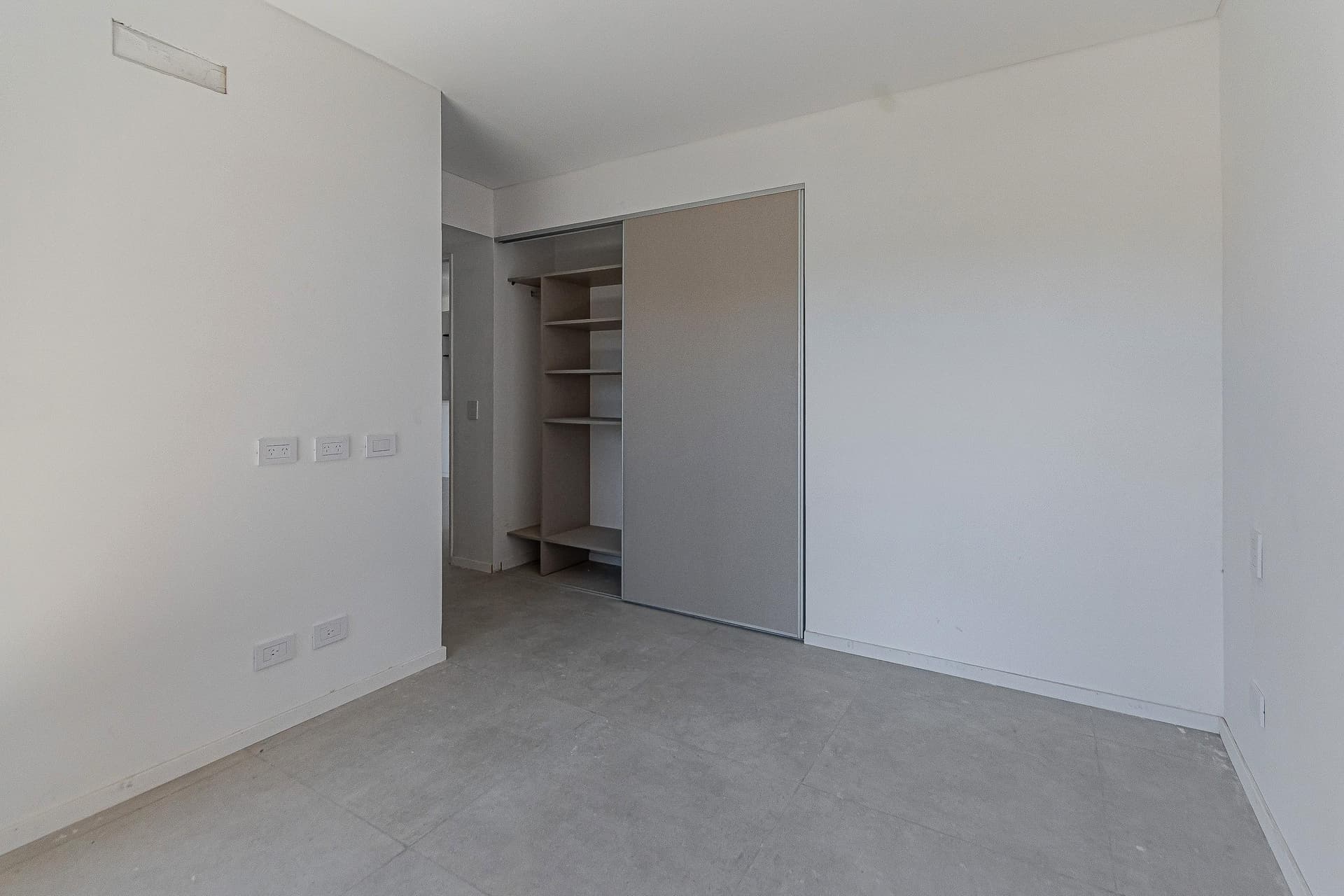 Dormitorio vacío con amplio placard empotrado y paredes blancas.