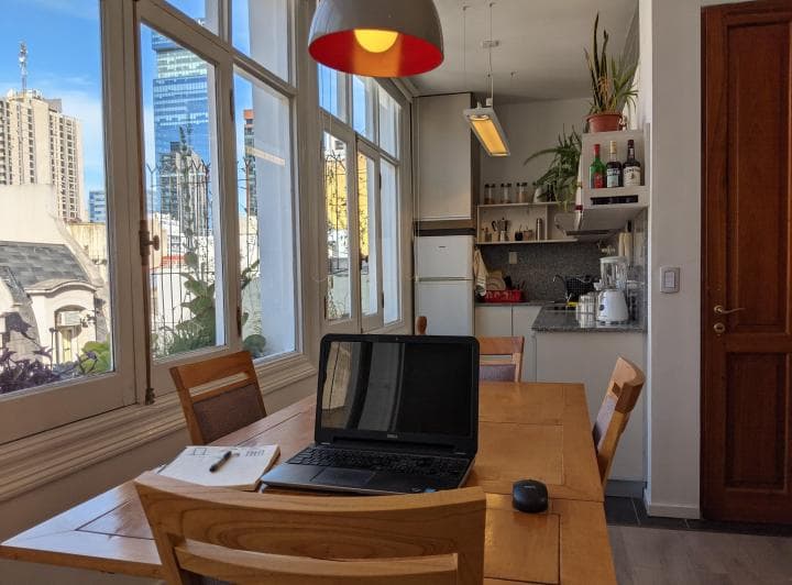 Cocina integrada con mesa de comedor, ventanales y vista a la ciudad.