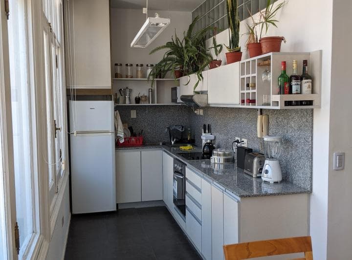 Cocina completa con mesada, heladera, anafe y alacenas blancas.