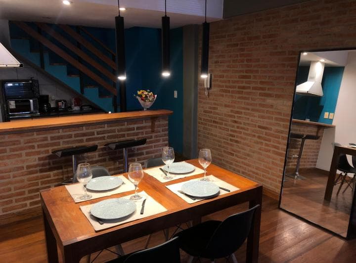 Cocina integrada con barra, banquetas, campana extractora y mesa de comedor.