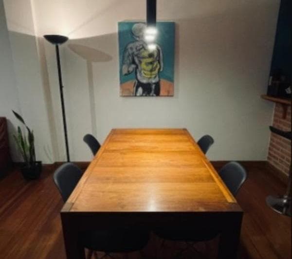 Comedor con mesa de madera, cuatro sillas y cuadro en la pared.