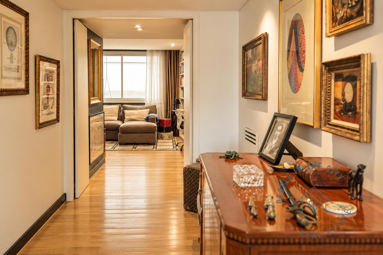 Pasillo decorado con cuadros y vista hacia una habitación.
