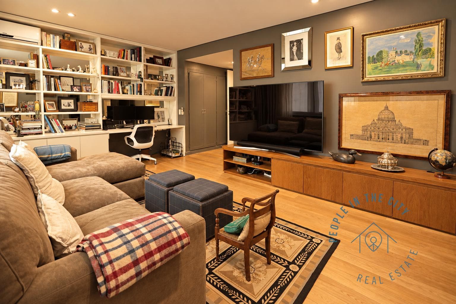Dormitorio o estudio con sofá en L, escritorio y estanterías con libros.