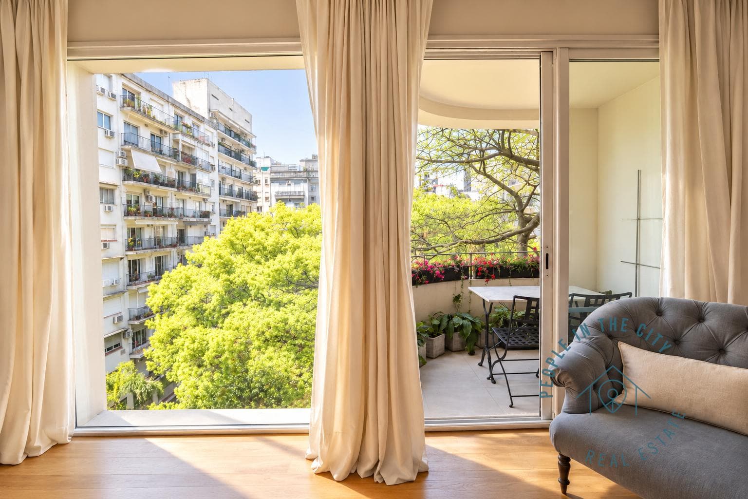 Balcón exterior con mesa y sillas, con vista a la ciudad.