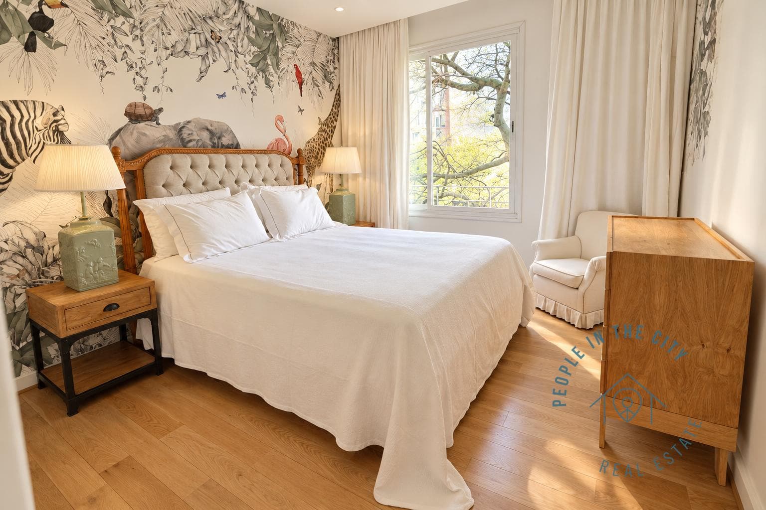 Dormitorio con cama, pared decorada con animales y ventana.