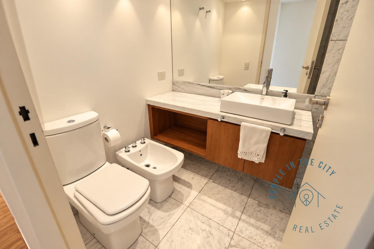 Baño completo con inodoro, bidet y bacha sobre mesada de mármol.