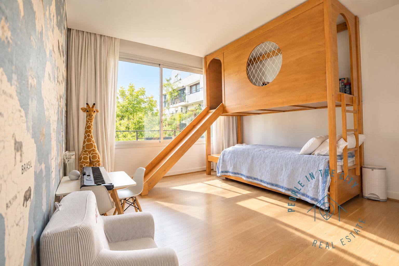 Dormitorio infantil con cama cucheta con tobogán y escritorio.
