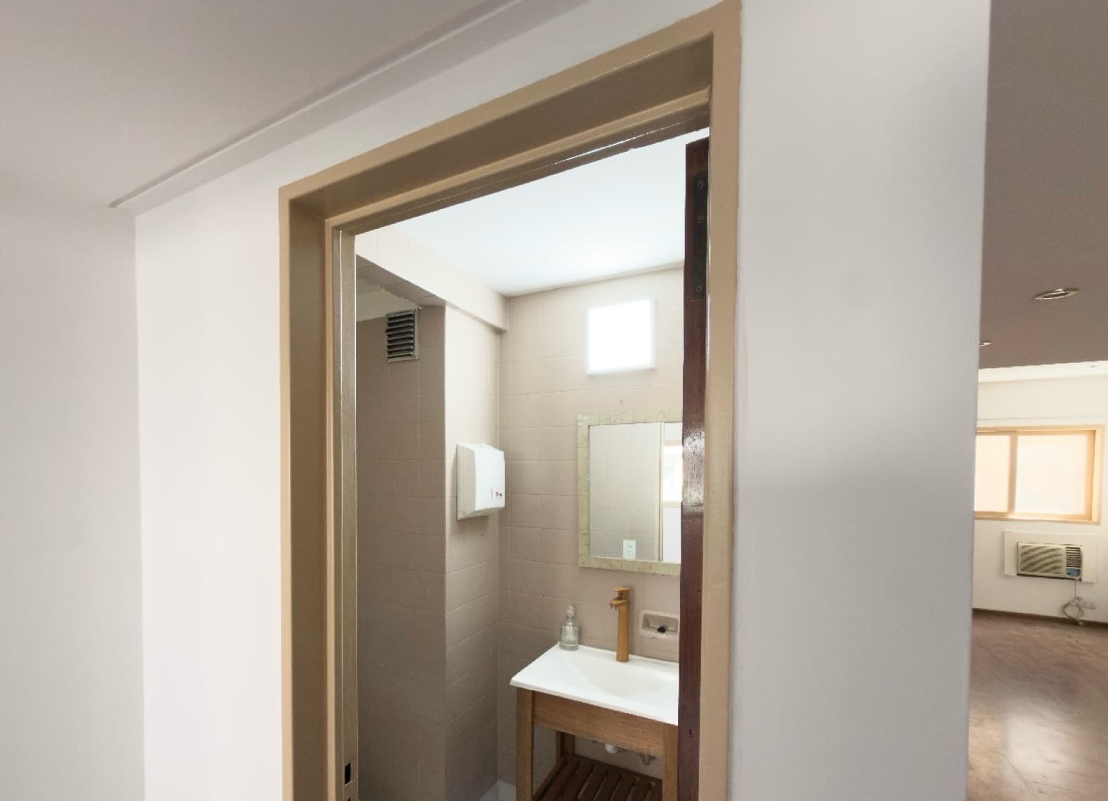 Toilette con lavatorio de madera, inodoro, espejo y toallero.
