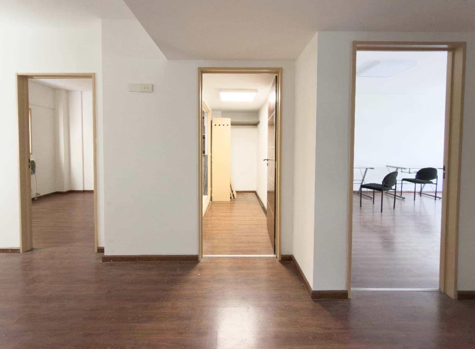 Pasillo con múltiples puertas de madera que conducen a habitaciones vacías.