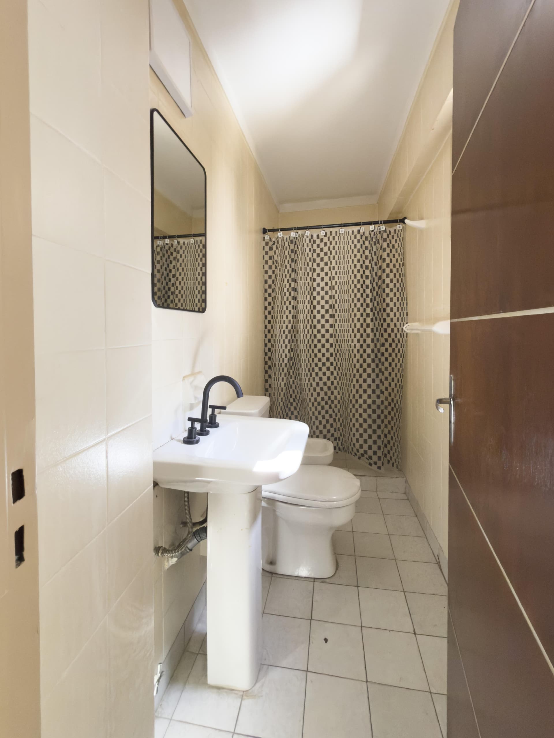 Baño completo con lavatorio, inodoro, bidet y cortina de ducha.