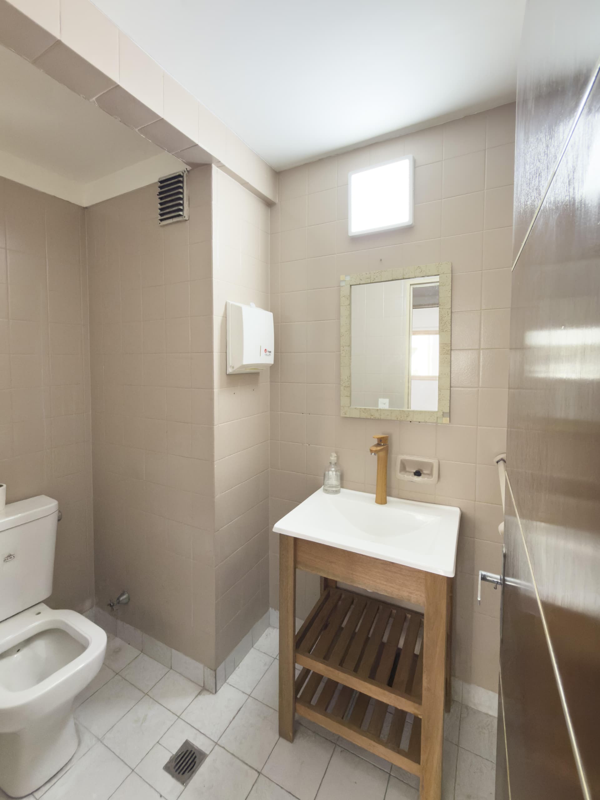 Toilette con lavatorio de madera, inodoro, espejo y toallero.
