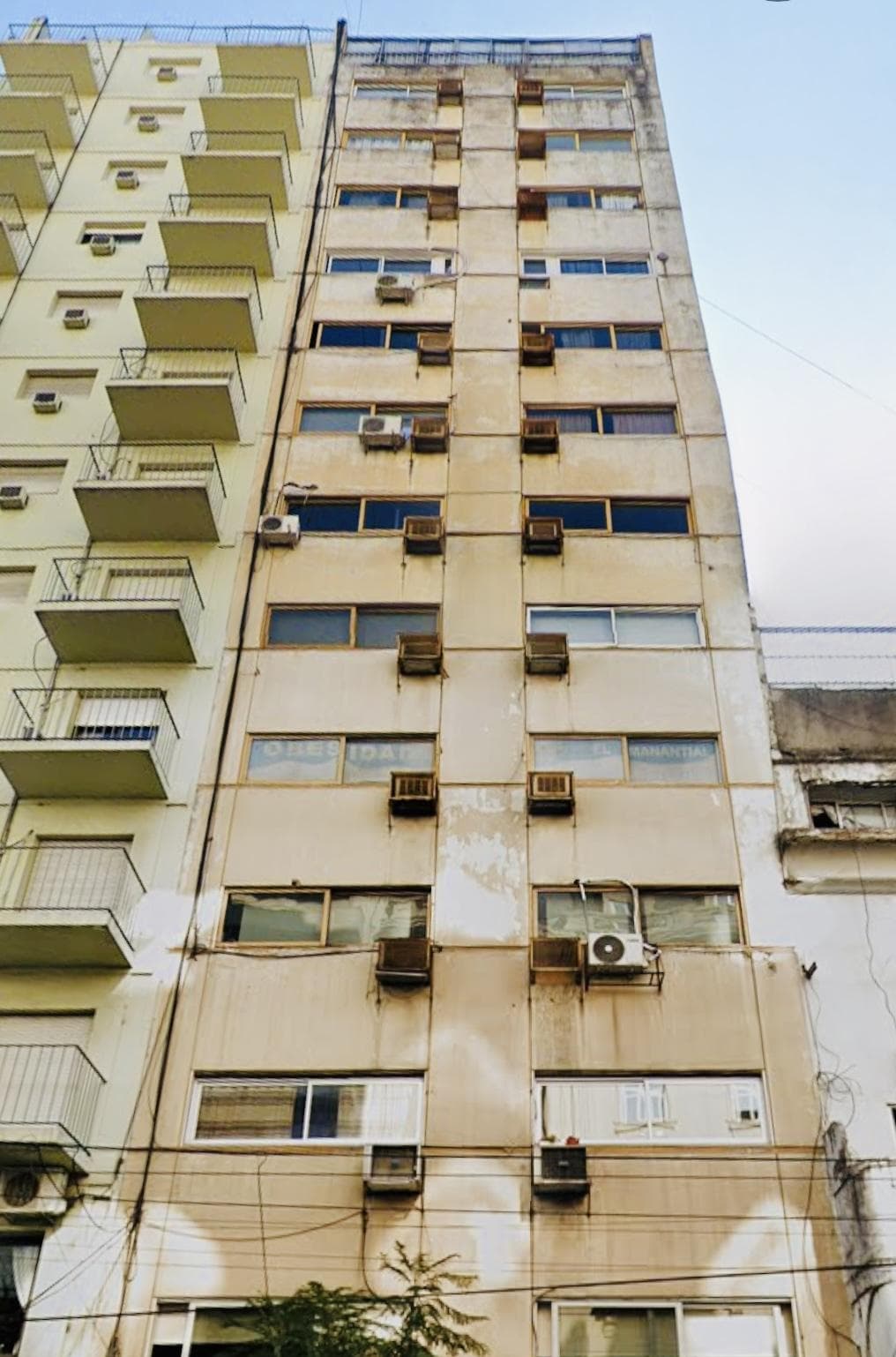 Fachada de un edificio alto con múltiples ventanas y aires acondicionados.