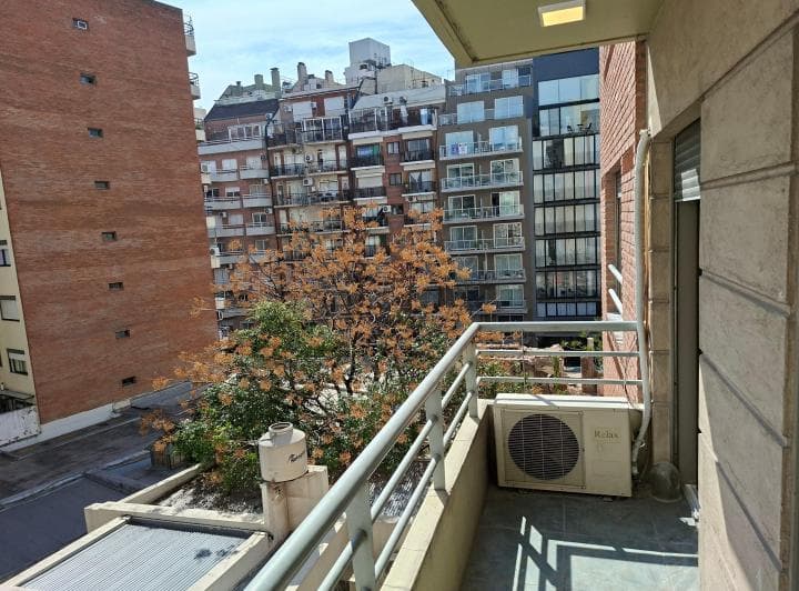 Balcón exterior del departamento con baranda metálica y vistas a la ciudad.