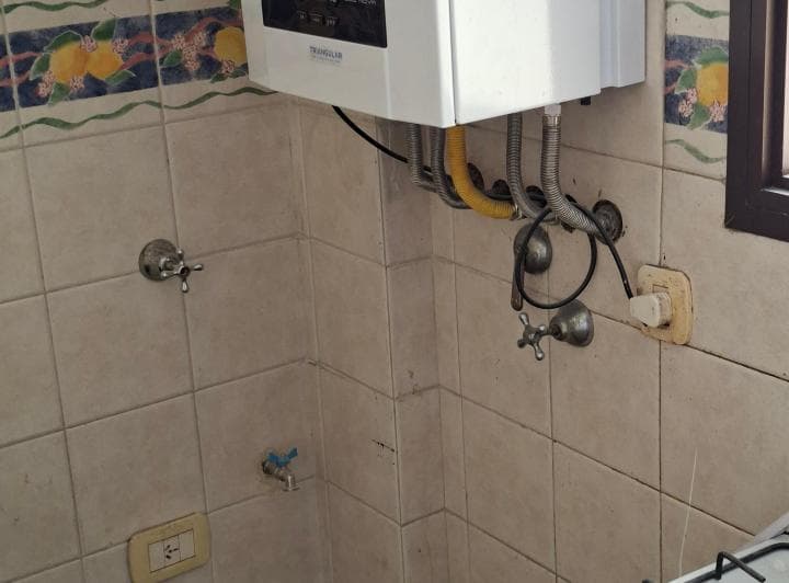 Detalle del termotanque, grifería y azulejos en la pared de la cocina.