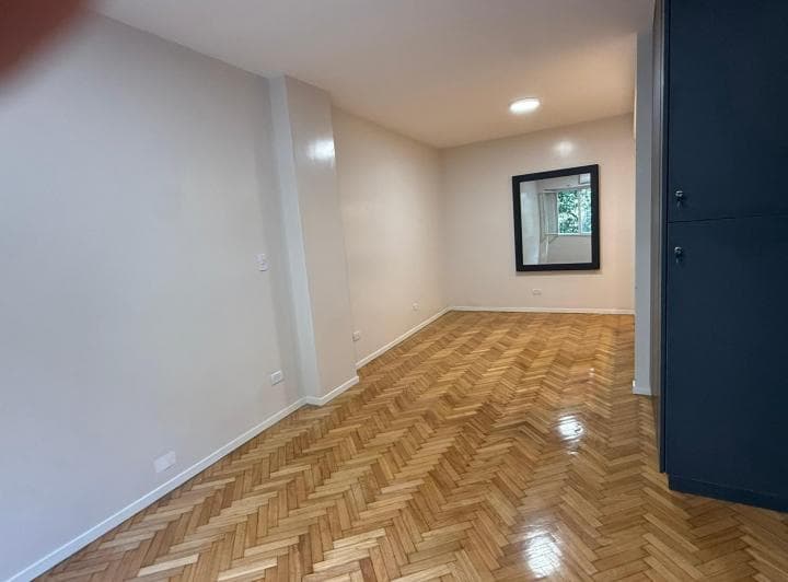 Living con piso de madera, espejo de pared y placard empotrado.
