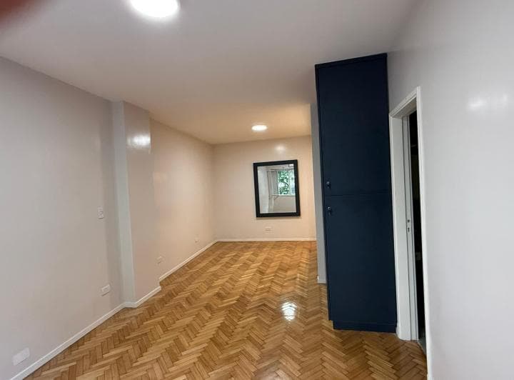 Living con espejo de pared y placard en la entrada, piso de madera.