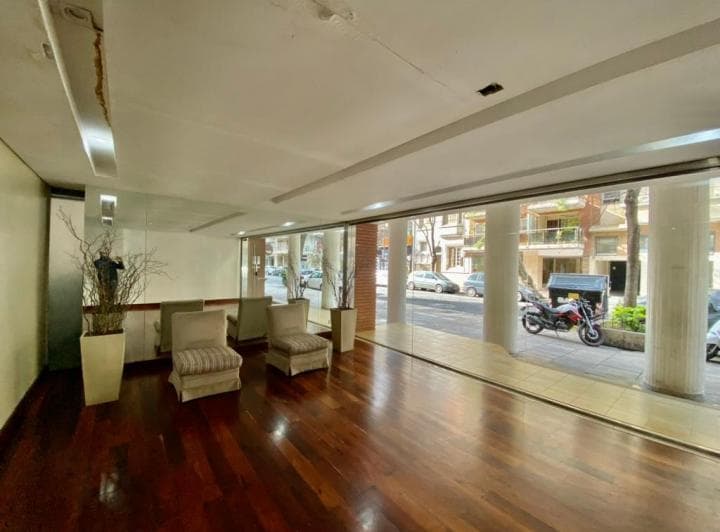Hall de entrada del edificio con sillones, ventanales y columnas.