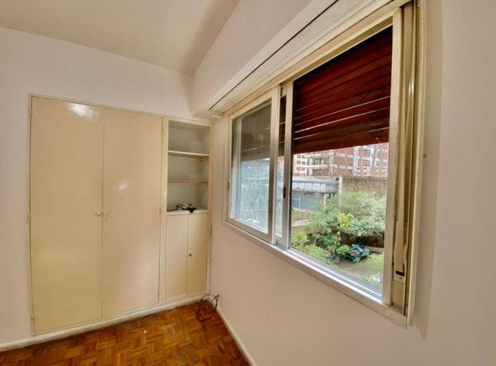 Dormitorio con ventana al jardín, placard empotrado y piso de parquet.