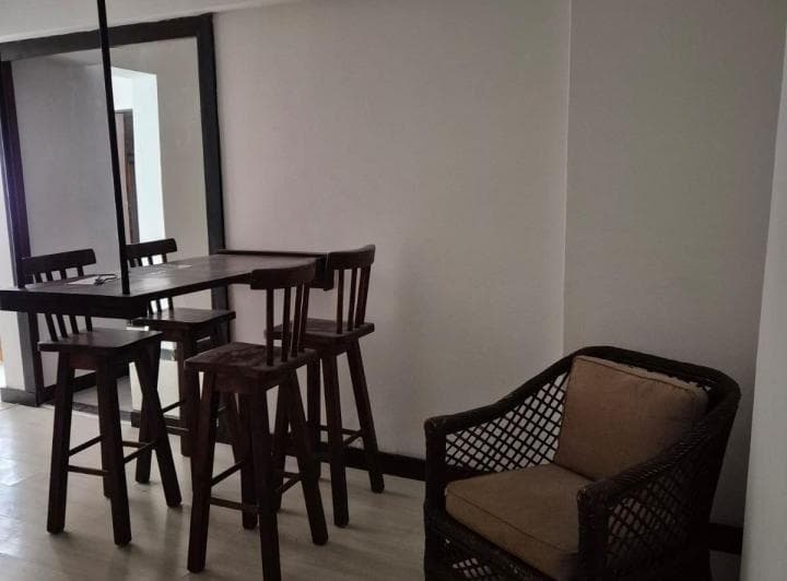 Living con barra y banquetas de madera, y sillón individual de mimbre.