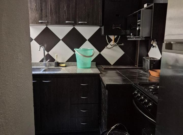 Cocina con mesada de granito, bacha y anafe, alacenas oscuras y azulejos.