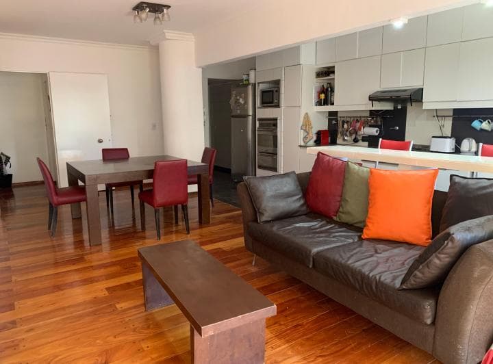 Living comedor amplio con cocina integrada y piso de madera.