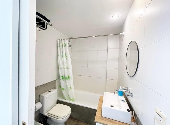 Baño con bañera, inodoro, vanitory con bacha y espejo redondo