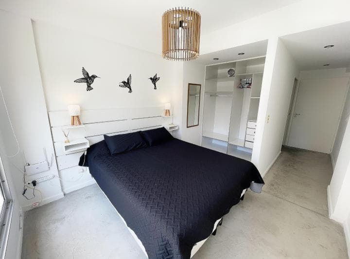 Dormitorio con cama doble, respaldo de madera y placard abierto