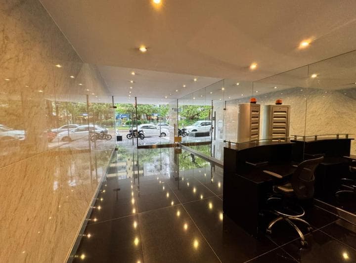 Hall de entrada del edificio con recepción, espejos y piso de mármol negro.