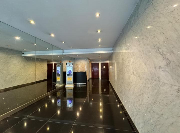 Pasillo principal del edificio con paredes de mármol y puertas de ascensores.