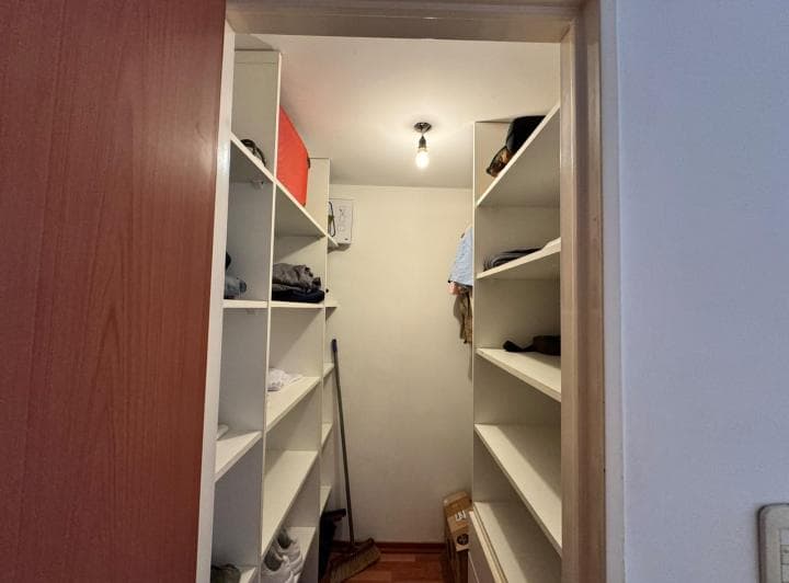 Vestidor vacío con estantes a ambos lados, luz colgante y piso de madera.