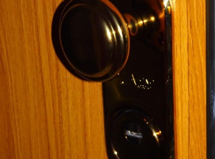 Primer plano de un picaporte y cerradura oscuros en una puerta de madera.