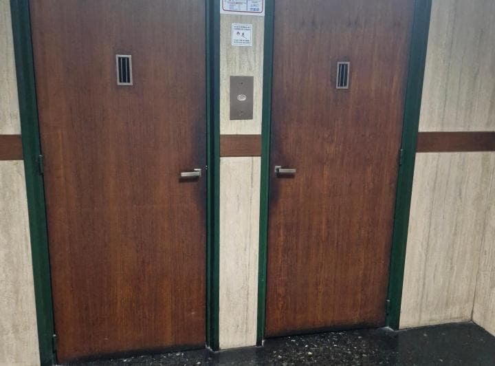 Palier del edificio con dos puertas de ascensor de madera.