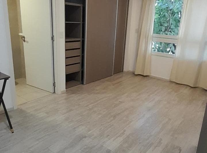 Dormitorio vacío con placard abierto y ventana con vista al exterior.