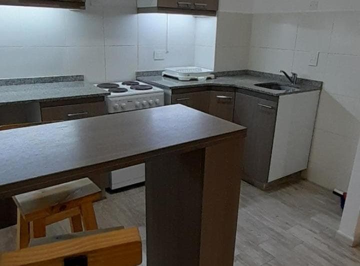 Cocina con anafe eléctrico, bacha, mesada de granito, alacenas y barra.