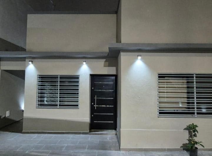 Fachada de casa con puerta de entrada y ventanas con rejas.