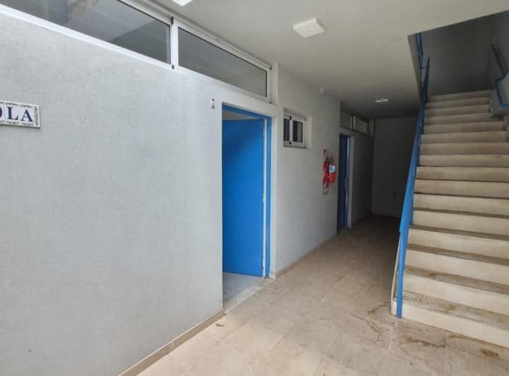 Pasillo de entrada con escaleras y puertas azules.