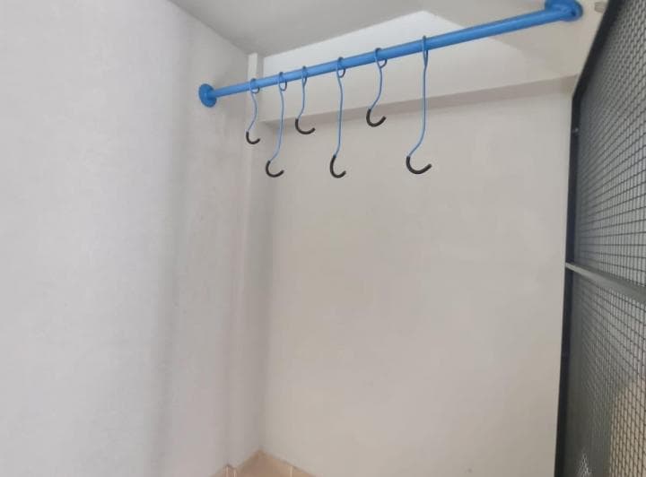 Lavadero con barra azul y ganchos en la pared.
