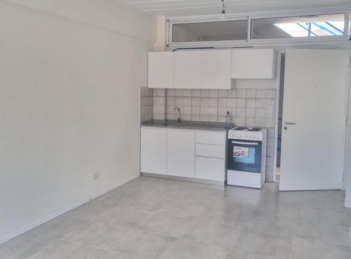 Living de un ambiente vacío con cocina integrada.