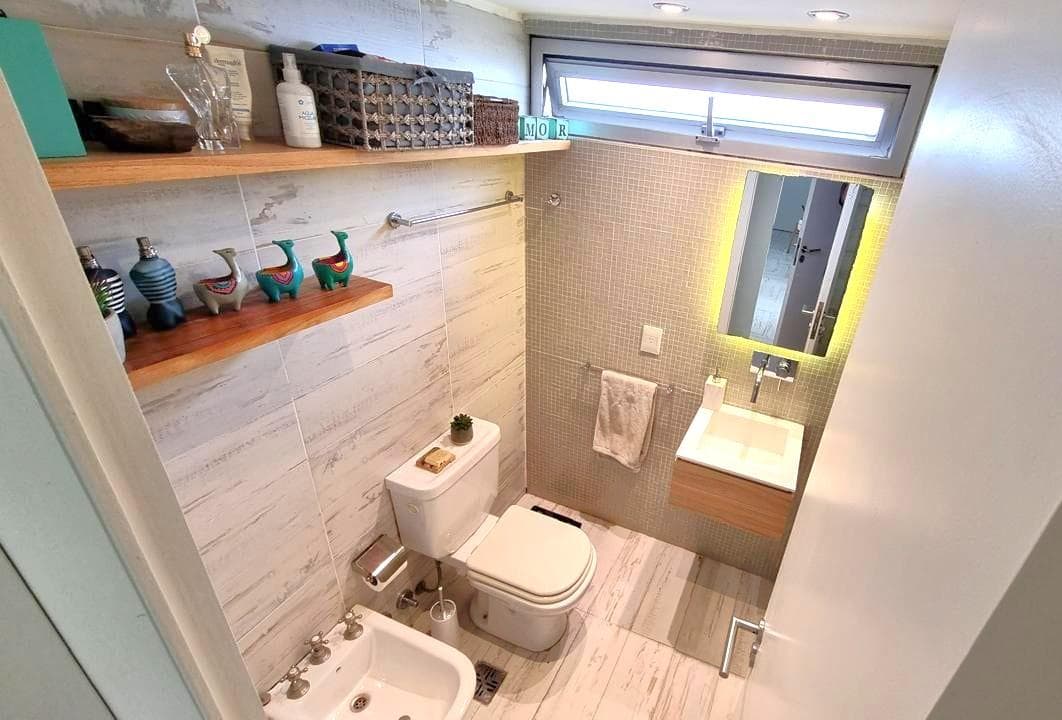 Baño completo con inodoro, bidet, vanitory, espejo iluminado y ventana.