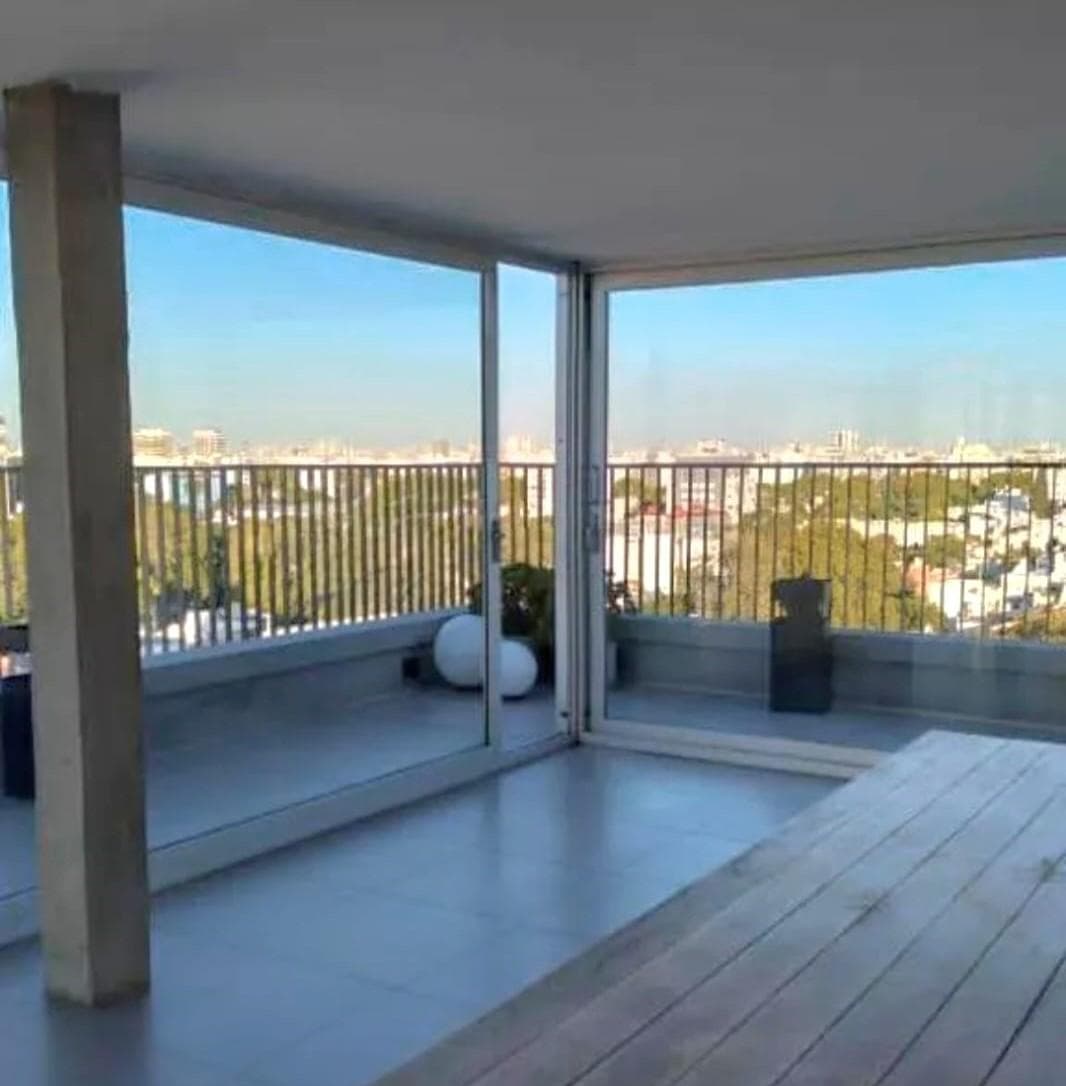 Espacio común con amplio ventanal, balcón y vista panorámica de la ciudad.