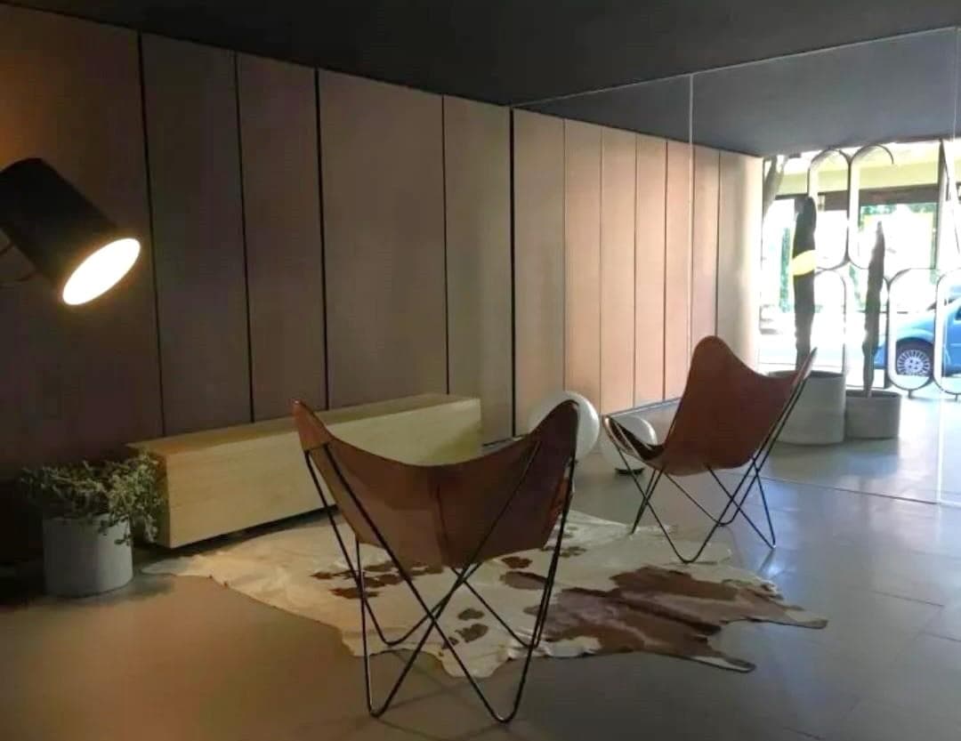 Hall de entrada con sillones de cuero, alfombra de piel y pared de madera.