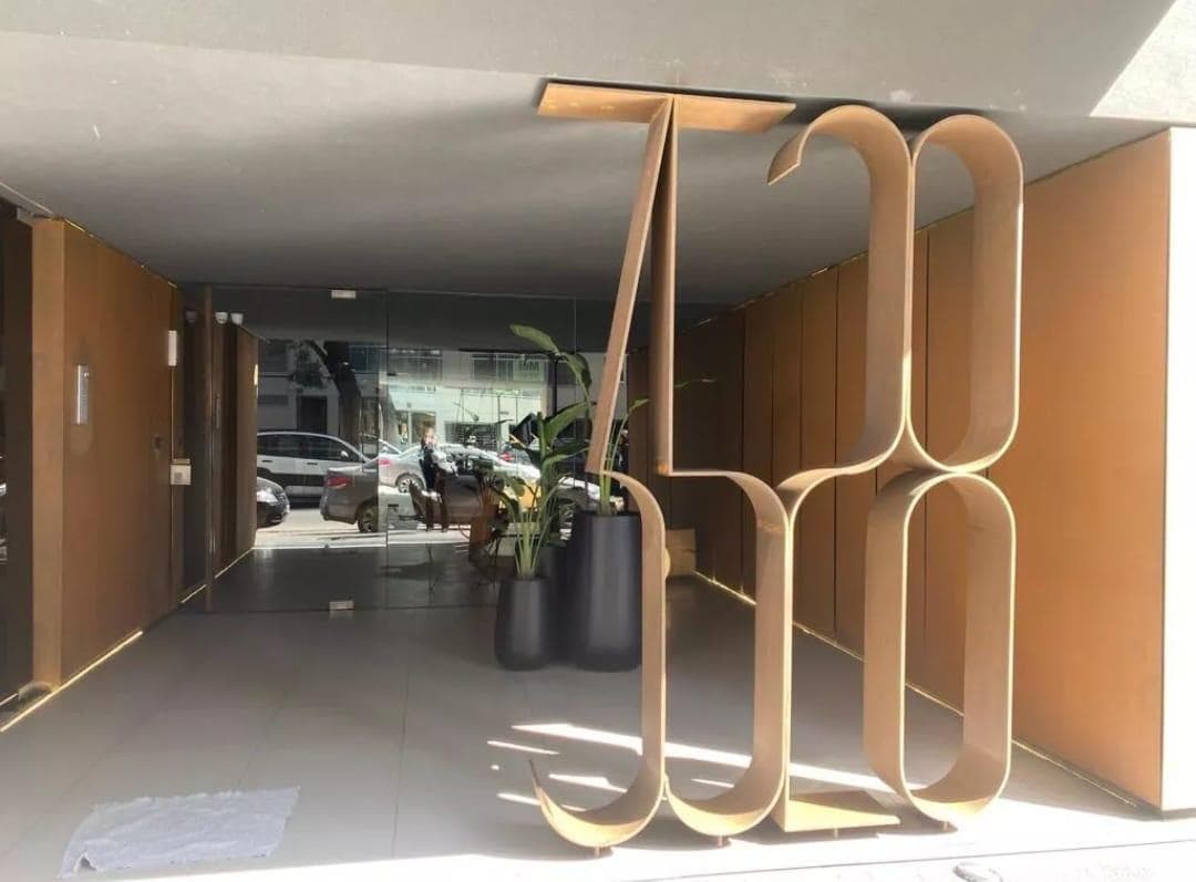 Entrada al edificio con cartel de metal y puerta de vidrio.