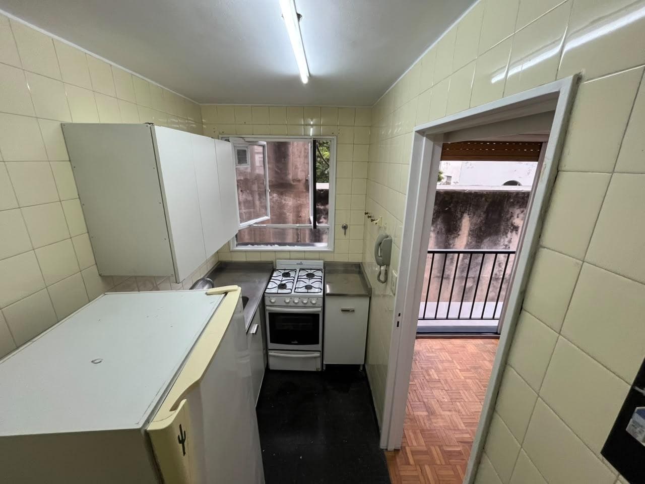 Cocina con heladera, anafe, horno, ventana y vista al living.
