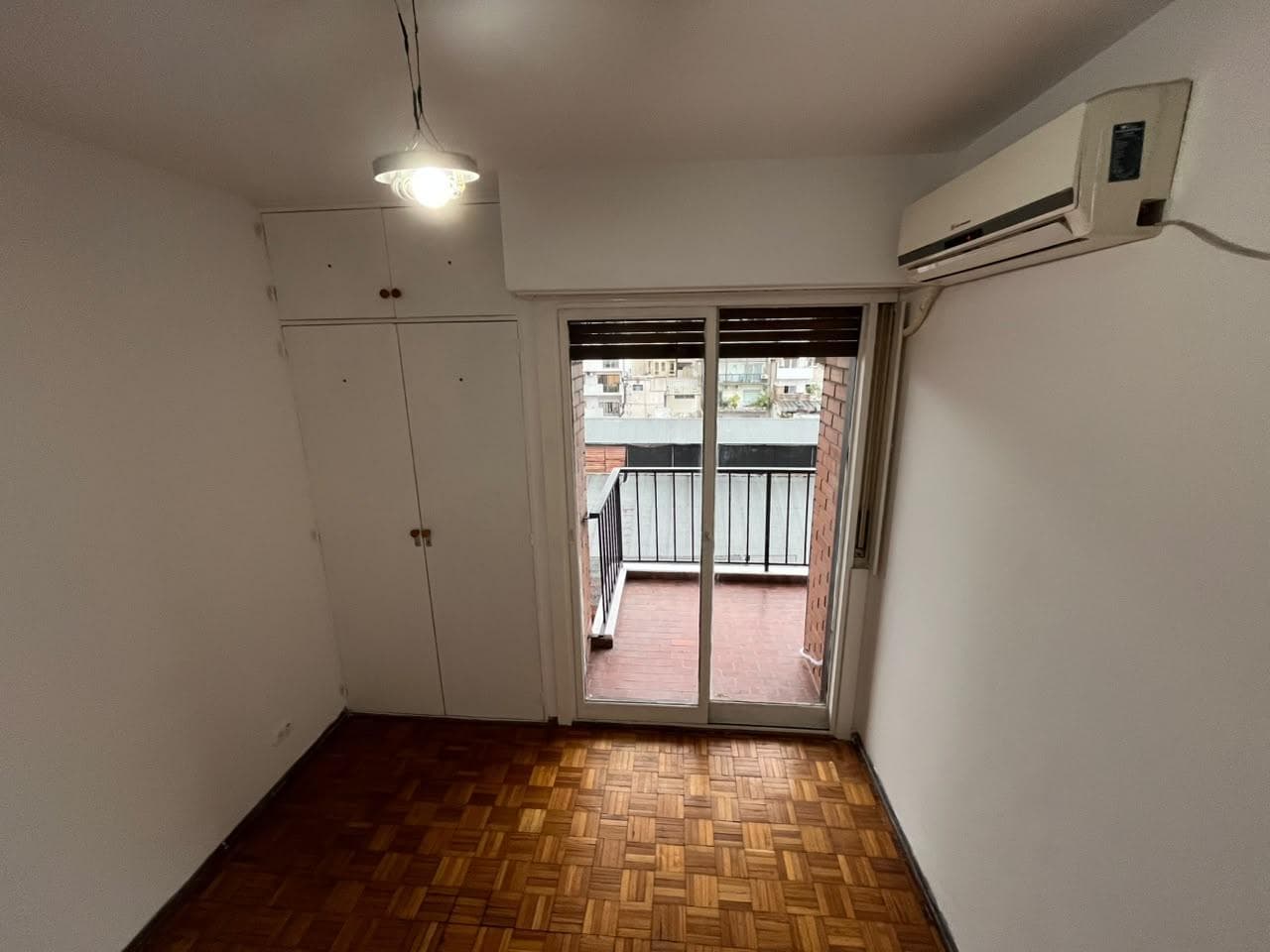 Dormitorio con placard, piso de parquet, ventana al balcón.