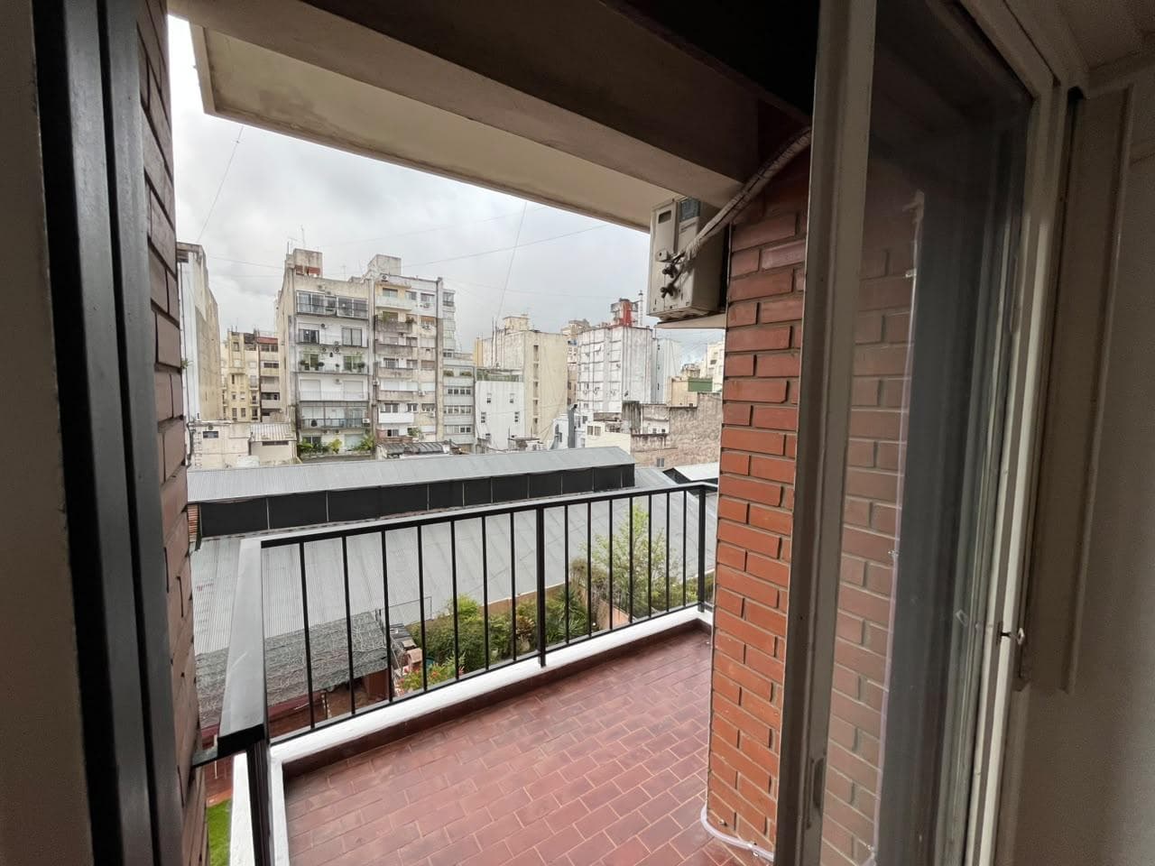 Balcón con vista a edificios de la ciudad y patio verde.