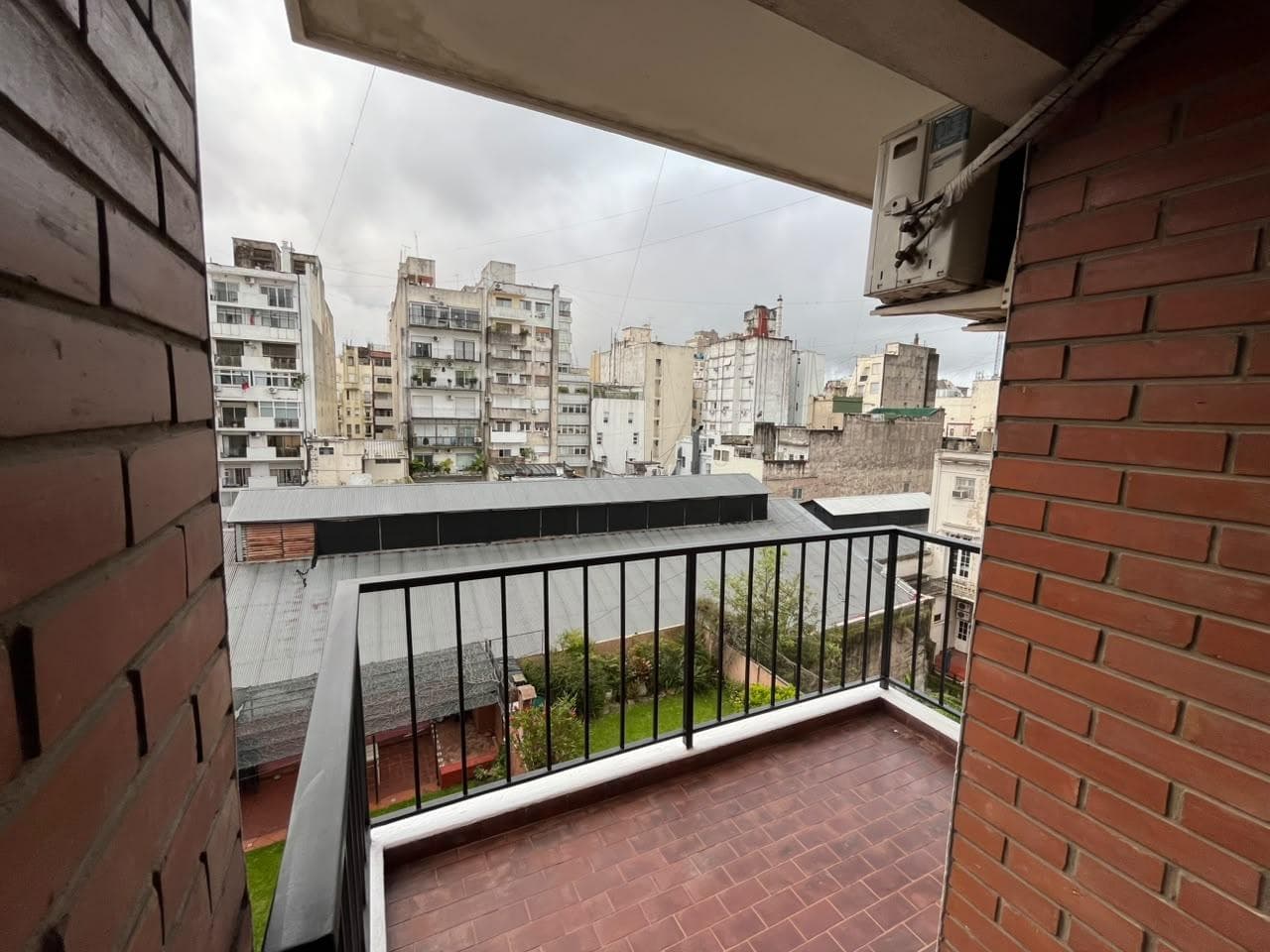 Balcón con vista a edificios y patio con césped.