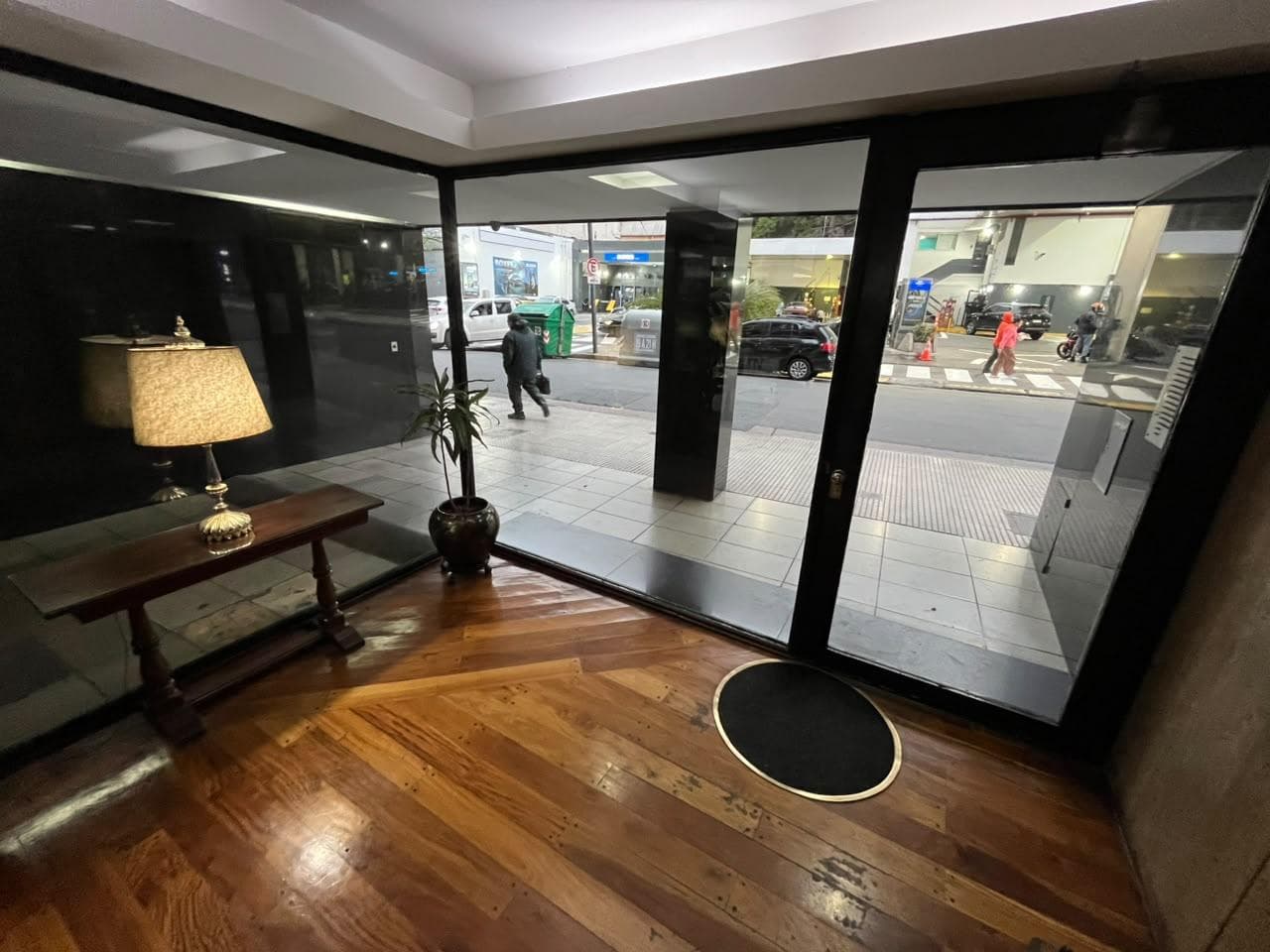 Hall de entrada del edificio con piso de madera y ventanales.