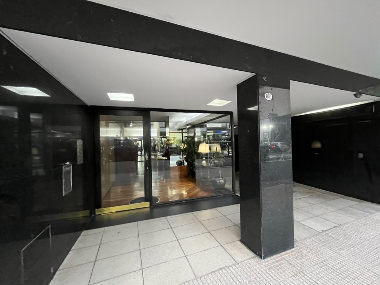 Fachada del edificio con entrada de vidrio y mármol negro.
