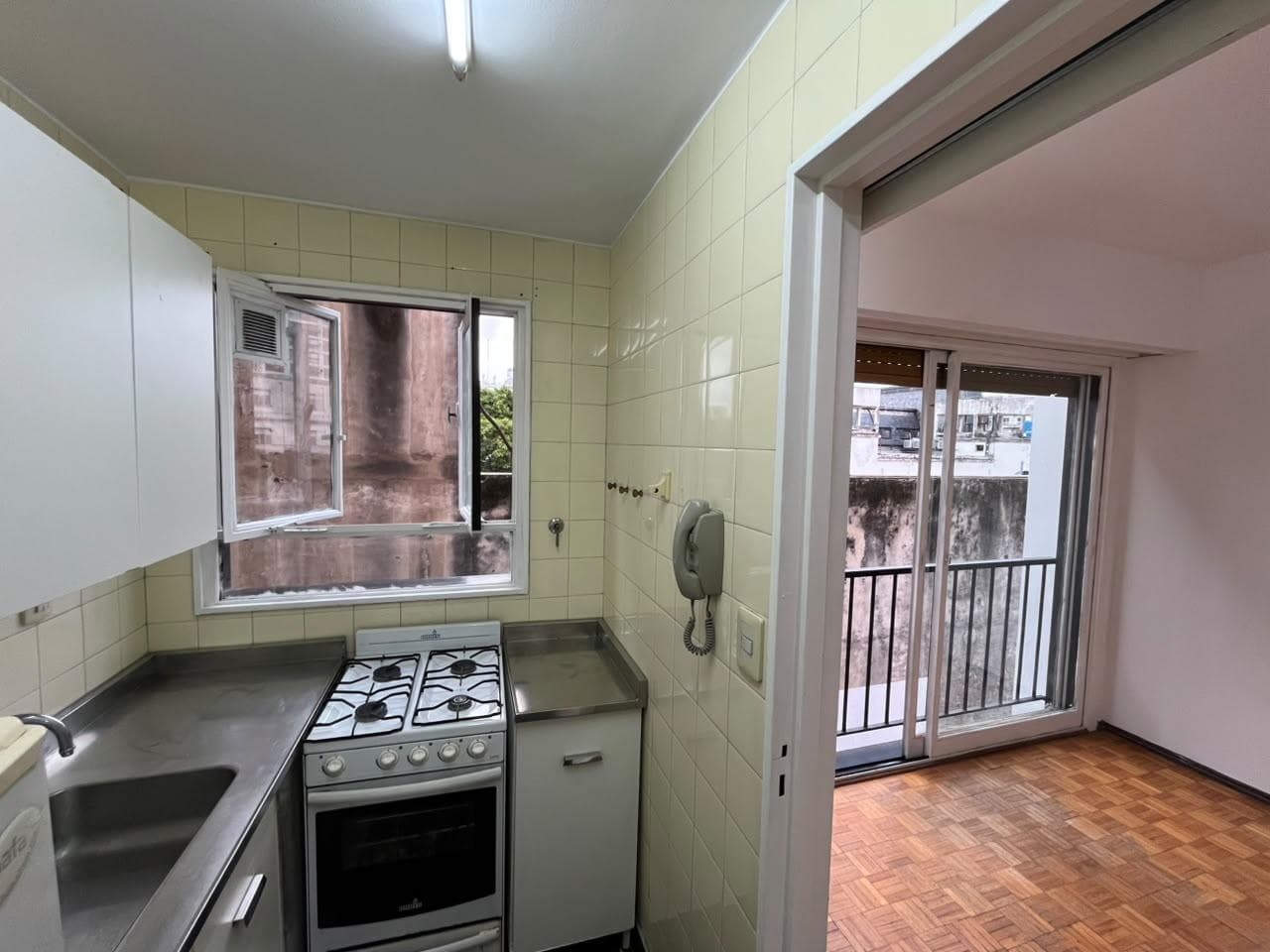 Cocina con mesada, bacha, anafe, horno, alacena y ventana.
